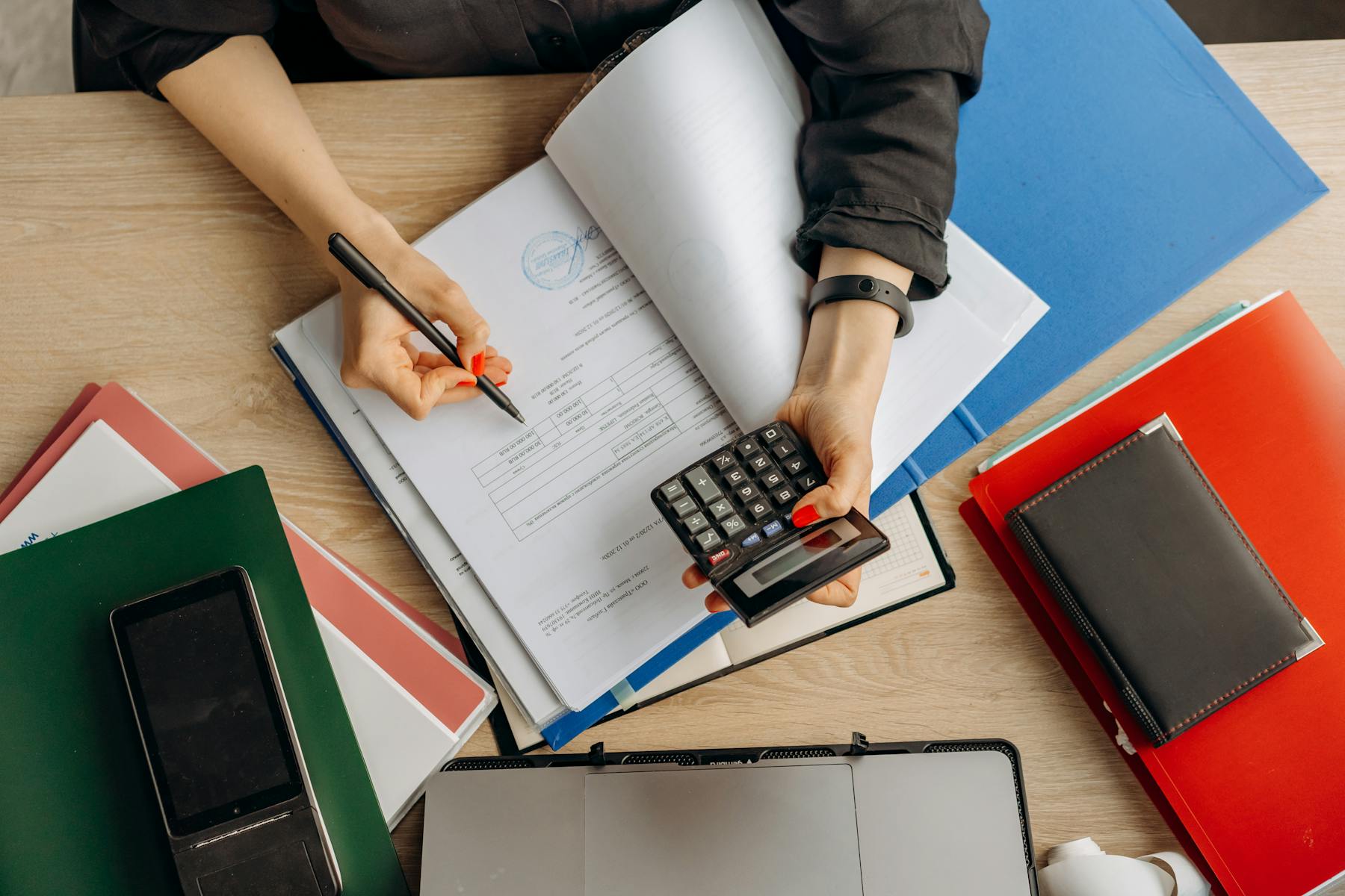 Business owner reviewing accounting system reports with a calculator and laptop.